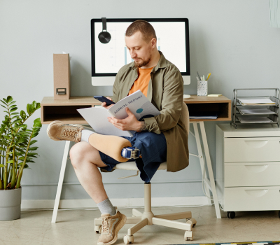 Фотография мужчины сидящего на стуле в положении нога на ноге, с протезом бедра