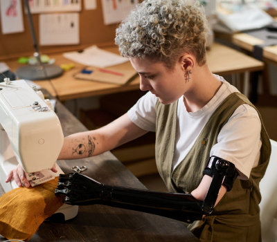Фотография девушки занимающейся шитьем с помощью бионического протеза руки